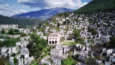 Olludeniz yakınlarındaki dünyaca ünlü Kayakoy hayalet kasabasının insansız hava aracı görüntüsü, Fethiye. Tepenin güzel yeşil yamacındaki antik şehir..