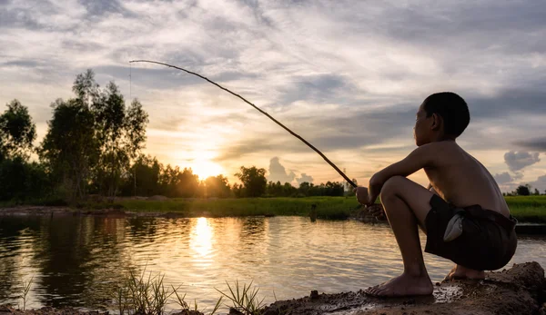 Boy fishing  in sunset — Stock Photo, Image