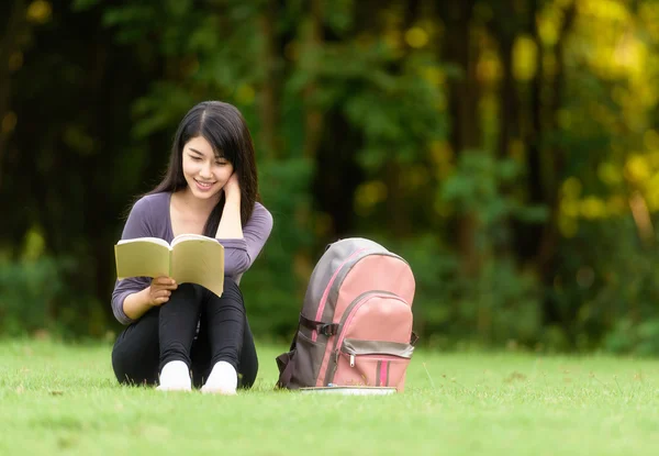 Porträt einer glücklichen, charmanten Thailänderin, die im Freien ein Buch liest — Stockfoto