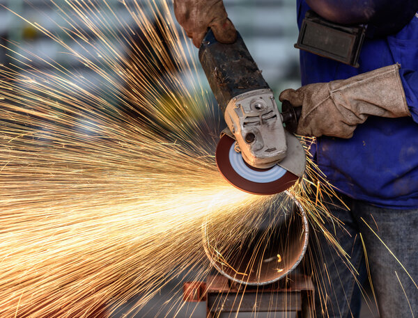 Electric wheel grinding on steel structure in factory