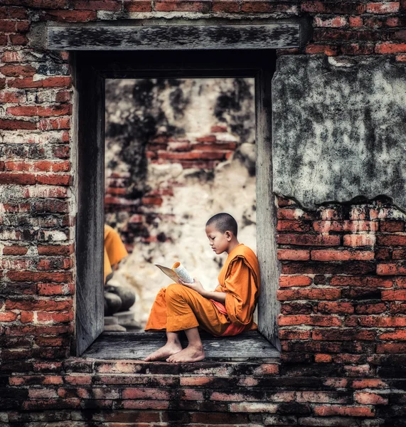 Südostasiatischer Novizenmönch liest Buch vor dem Kloster — Stockfoto