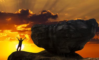 adam büyük kaya ile dağın zirvesinde