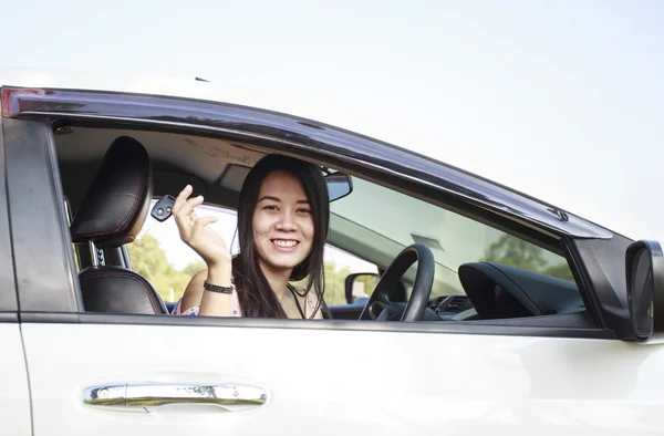 Азиатская женщина-водитель улыбается, показывая ключи от новой машины — стоковое фото