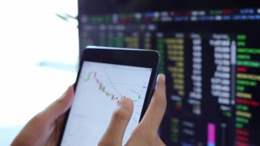 Yatırımcılar hisse senedi ticareti yapıyor. Akıllı telefonlar ve bilgisayarlar kullanarak