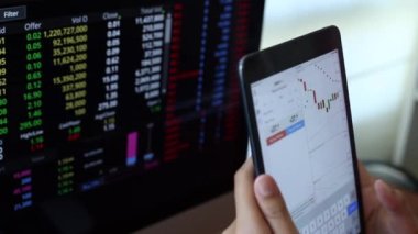 Yatırımcılar hisse senedi ticareti yapıyor. Akıllı telefonlar ve bilgisayarlar kullanarak