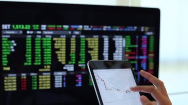 Yatırımcılar hisse senedi ticareti yapıyor. Akıllı telefonlar ve bilgisayarlar kullanarak