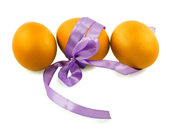 Drie eieren en een paarse lint geïsoleerd op witte achtergrond — Stockfoto
