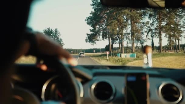 Al rallentatore. Vista posteriore al giovane che si diverte a viaggiare in macchina durante il tramonto. Un uomo che guida un veicolo. I raggi solari brillano attraverso il parabrezza del veicolo. — Video Stock