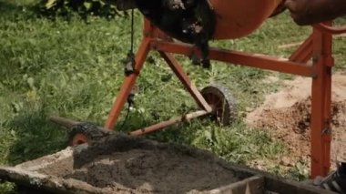 Sedyenin üzerine hazır beton dökülüyor. Küçük taşınabilir çimento karıştırma makinesi. Evde çimento karıştırıyorum. Yeşil bulanık arkaplan
