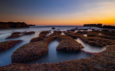Arka plan için inanılmaz bir deniz manzarası. Taşları ve taşları olan bir sahil. Dalgalar çekildi. Hareket suyu. Açık renkli gökyüzü. Kapama hızı yavaş. Yumuşak odaklanma. Mengening Plajı, Bali, Endonezya