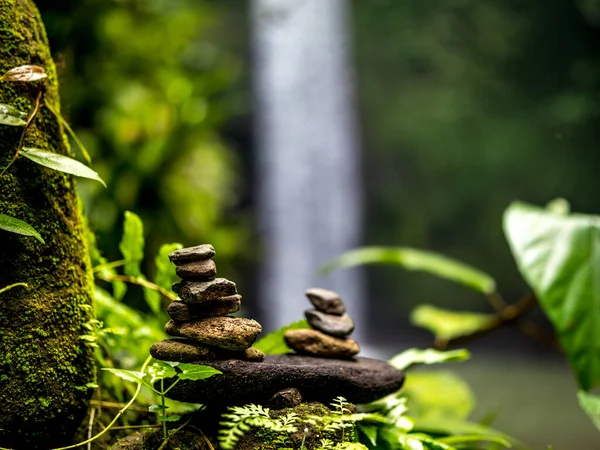 Balance stones in tropical forest. Peaceful nature. Background with blurred waterfall. Beatiful tropical landscape. Selected focus. Horizontal layout. Tibumana waterwall in Bali, Indonesia — Stock Image Balance Stones Tropical Forest Peaceful Nature Background Blurred Waterfall Beatiful Stock Picture
