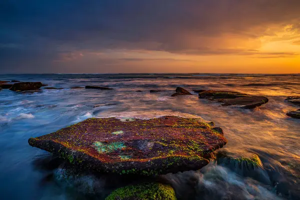 美丽的海景 岩石和石头 被海藻覆盖的平坦的大石头 移动的水 多云的天空 自然概念 慢速快门速度 集中精神印度尼西亚巴厘Mengening海滩 — 图库照片