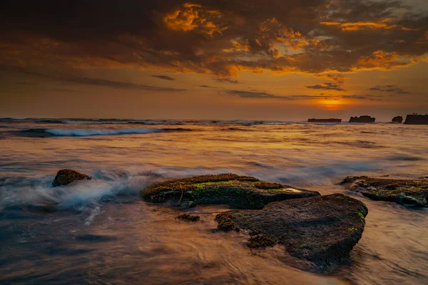 平静的海洋长期暴露 巨石在海浪的神秘薄雾中飘扬 自然背景的概念 日落背景 地平线上的太阳集中精神多云的天空 Mengening海滩 印度尼西亚巴厘 — 图库照片