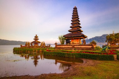 Bali adasındaki Pura Ulun Danu Bratan tapınağı. Güzel bale tapınağı. Bali 'nin simgesi. Bulutlu gökyüzü. Su yansıması. Yeşil çimenli ön plan. Bratan Gölü, Bedugul, Bali, Endonezya