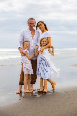 Kumsalda mutlu bir aile. Anne, baba ve kızları birlikte güzel vakit geçiriyorlar. Yaz tatili. Asya 'da aile tatili. Aileler çocukları kucaklıyor. Seyahat konsepti. Uzayı kopyala Bali, Endonezya
