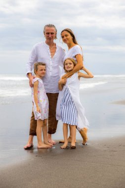 Kumsalda mutlu bir aile. Anne, baba ve kızları birlikte güzel vakit geçiriyorlar. Yaz tatili. Asya 'da aile tatili. Aileler çocukları kucaklıyor. Seyahat konsepti. Uzayı kopyala Bali, Endonezya