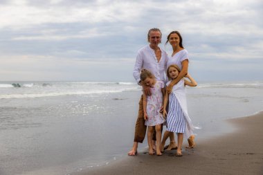 Kumsalda mutlu bir aile. Anne, baba ve kızları birlikte güzel vakit geçiriyorlar. Yaz tatili. Asya 'da aile tatili. Aileler çocukları kucaklıyor. Seyahat konsepti. Uzayı kopyala Bali, Endonezya