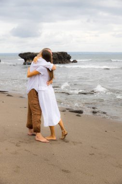 Karı koca kucaklaşır. Aşık romantik bir çift. Aile ilişkisi kavramı. Gün batımında sahilde çıplak ayaklı bir çift. Asya 'da tatil. Birlikte seyahat edin. Bali, Endonezya