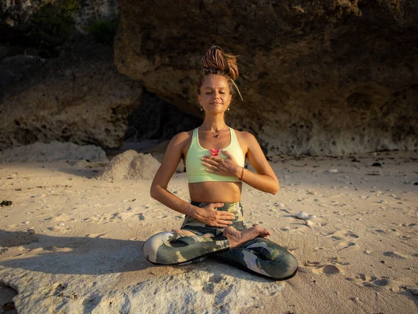 Meditasyon ve pranayama. Kumda oturan beyaz bir kadın, nefes alma teknikleri uyguluyor. Sahilde yoga. Sağlıklı bir yaşam tarzı. Kişisel bakım ve olumlu duygular. Endonezya, Bali 'de geri çekilme