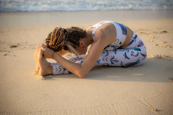 Plaj yogası Paschimottanasana egzersizi yapan beyaz bir kadın, öne eğilip poz veriyor. Esnek vücut. Esneme egzersizi. Omurga sağlam. Bali 'de yoga inzivası. Uzayı kopyala Thomas Sahili, Endonezya