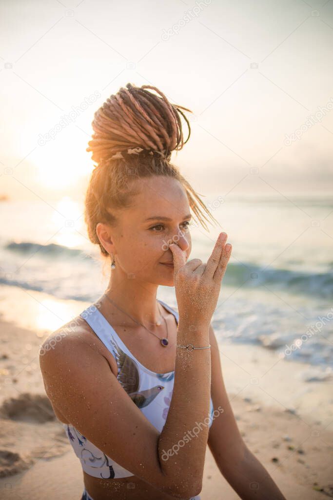 Yogi woman practicing Nadi Shodhana Pranayama, Alternate Nostril Breathing. Control prana, control of breath. Breathing exercise. Self care concept. Sunset time. Yoga retreat. Thomas beach, Bali