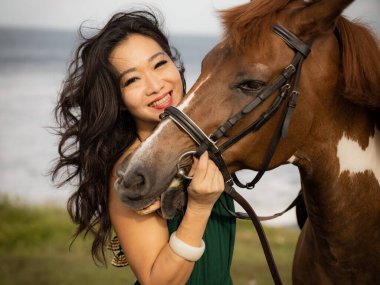 Portrait of happy smiling woman and brown horse. Asian woman hugging horse. Romantic concept. Love to animals. Nature concept. Bali, Indonesia clipart
