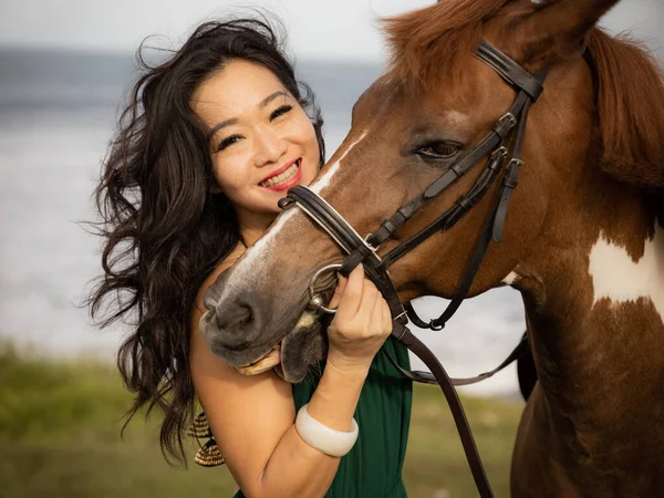 Portrait of happy smiling woman and brown horse. Asian woman hugging horse. Romantic concept. Love to animals. Nature concept. Bali, Indonesia