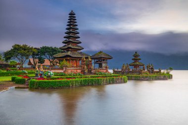 Bali adasındaki Pura Ulun Danu Bratan tapınağı. Güneş doğarken çok güzel bir bale tapınağı. Bali 'nin simgesi. Bulutlu gökyüzü. Su yansıması. Kapama hızı yavaş. Bratan Gölü, Bali, Endonezya