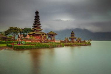 Bali adasındaki Pura Ulun Danu Bratan tapınağı. Güneş doğarken çok güzel bir bale tapınağı. Bali 'nin simgesi. Bulutlu gökyüzü. Su yansıması. Kapama hızı yavaş. Bratan Gölü, Bali, Endonezya