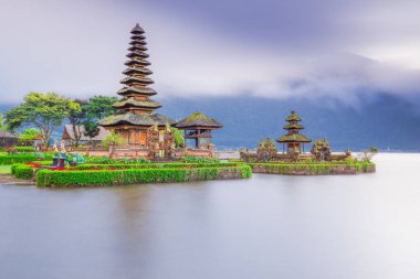 Bali adasındaki Pura Ulun Danu Bratan tapınağı. Güneş doğarken çok güzel bir bale tapınağı. Bali 'nin simgesi. Bulutlu gökyüzü. Su yansıması. Kapama hızı yavaş. Bratan Gölü, Bali, Endonezya