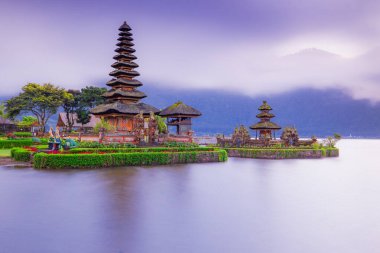 Bali adasındaki Pura Ulun Danu Bratan tapınağı. Güneş doğarken çok güzel bir bale tapınağı. Bali 'nin simgesi. Bulutlu gökyüzü. Su yansıması. Kapama hızı yavaş. Bratan Gölü, Bali, Endonezya