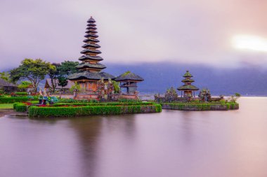 Bali adasındaki Pura Ulun Danu Bratan tapınağı. Güneş doğarken çok güzel bir bale tapınağı. Bali 'nin simgesi. Bulutlu gökyüzü. Su yansıması. Kapama hızı yavaş. Bratan Gölü, Bali, Endonezya
