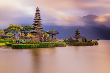 Bali adasındaki Pura Ulun Danu Bratan tapınağı. Güneş doğarken çok güzel bir bale tapınağı. Bali 'nin simgesi. Bulutlu gökyüzü. Su yansıması. Kapama hızı yavaş. Bratan Gölü, Bali, Endonezya