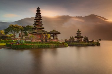 Bali adasındaki Pura Ulun Danu Bratan tapınağı. Güneş doğarken çok güzel bir bale tapınağı. Bali 'nin simgesi. Bulutlu gökyüzü. Su yansıması. Kapama hızı yavaş. Bratan Gölü, Bali, Endonezya