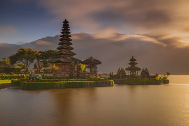 Bali adasındaki Pura Ulun Danu Bratan tapınağı. Güneş doğarken çok güzel bir bale tapınağı. Bali 'nin simgesi. Bulutlu gökyüzü. Su yansıması. Kapama hızı yavaş. Bratan Gölü, Bali, Endonezya