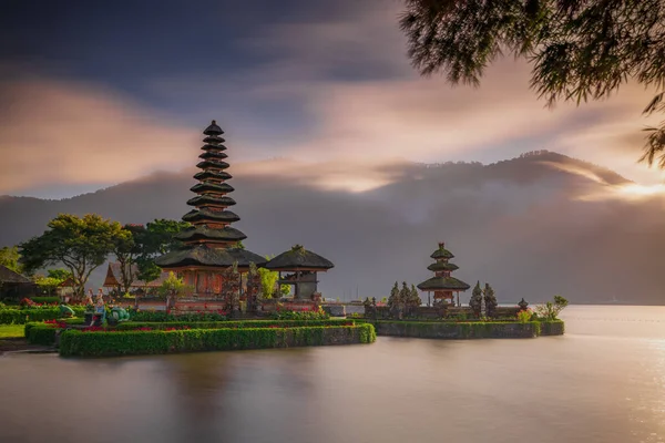Bali adasındaki Pura Ulun Danu Bratan tapınağı. Güzel bale tapınağı. Bali 'nin simgesi. Bulutlu gökyüzü. Su yansıması. Bambu dallı ön plan. Bratan Gölü, Bedugul, Bali, Endonezya