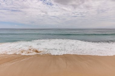 Deniz manzaralı arka plan. Kumsal, süt köpüğü dalgaları, mavi okyanus. Manzaralı su manzarası. Ufuk çizgisi. Bulutlu gökyüzü. Doğa ve çevre kavramı. Gün ışığı. Uzayı kopyala Rüya Diyarı Sahili, Bali Endonezya