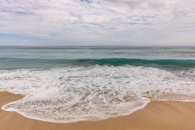 Deniz manzaralı arka plan. Kumsal, süt köpüğü dalgaları, mavi okyanus. Manzaralı su manzarası. Ufuk çizgisi. Bulutlu gökyüzü. Doğa ve çevre kavramı. Gün ışığı. Uzayı kopyala Rüya Diyarı Sahili, Bali Endonezya