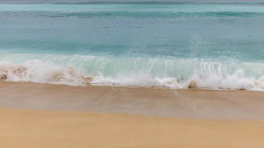 Deniz manzaralı arka plan. Kumsal, süt köpüğü dalgaları, mavi okyanus. Manzaralı su manzarası. Doğa ve çevre kavramı. Gün ışığı. Uzayı kopyala Rüya Diyarı Sahili, Bali Endonezya