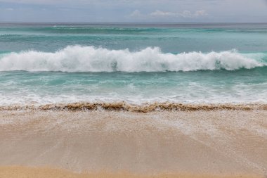 Deniz manzaralı arka plan. Kumsal, süt köpüğü dalgaları, mavi okyanus. Manzaralı su manzarası. Ufuk çizgisi. Doğa ve çevre kavramı. Gün ışığı. Uzayı kopyala Rüya Diyarı Sahili, Bali Endonezya