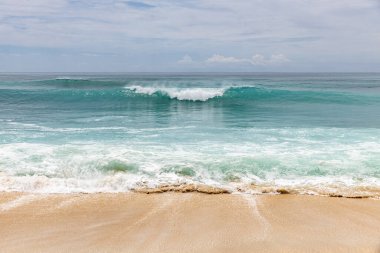 Deniz manzaralı arka plan. Kumsal, süt köpüğü dalgaları, mavi okyanus. Manzaralı su manzarası. Ufuk çizgisi. Bulutlu gökyüzü. Doğa ve çevre kavramı. Gün ışığı. Uzayı kopyala Rüya Diyarı Sahili, Bali Endonezya