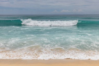Deniz manzaralı arka plan. Kumsal, süt köpüğü dalgaları, mavi okyanus. Manzaralı su manzarası. Ufuk çizgisi. Bulutlu gökyüzü. Doğa ve çevre kavramı. Gün ışığı. Uzayı kopyala Rüya Diyarı Sahili, Bali Endonezya