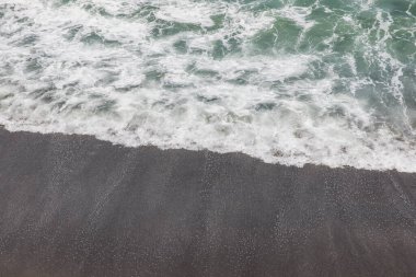 Waterscape arka planı. Beyaz süt köpüklü dalgalı siyah kumsal. Doğa ve çevre kavramı. Siyah ve beyaz kontrastı. Gün ışığı. Uzayı kopyala Endonezya, Bali 'deki volkanik plaj