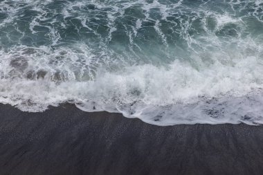 Waterscape arka planı. Beyaz süt köpüklü dalgalı siyah kumsal. Doğa ve çevre kavramı. Siyah ve beyaz kontrastı. Gün ışığı. Uzayı kopyala Endonezya, Bali 'deki volkanik plaj