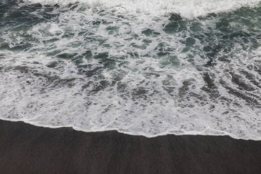 Waterscape arka planı. Beyaz süt köpüklü dalgalı siyah kumsal. Doğa ve çevre kavramı. Siyah ve beyaz kontrastı. Gün ışığı. Uzayı kopyala Endonezya, Bali 'deki volkanik plaj