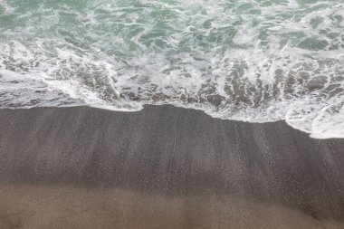 Waterscape arka planı. Beyaz süt köpüklü dalgalı siyah kumsal. Doğa ve çevre kavramı. Siyah ve beyaz kontrastı. Gün ışığı. Uzayı kopyala Endonezya, Bali 'deki volkanik plaj