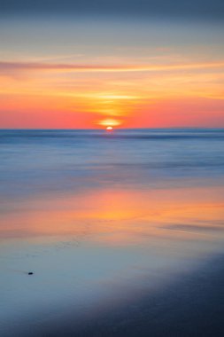 Gün batımı ve sahil. Deniz manzaralı arka plan. Parlak güneş ışığı. Güneş ufukta görünüyor. Manzaralı. Renkli gökyüzü. Suda güneş ışığı yansıması. Muhteşem bir manzara. Uzayı kopyala Bali, Endonezya
