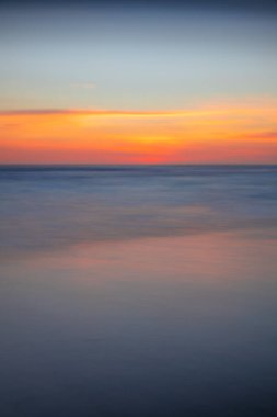 Gün batımı deniz manzarası. Kapama hızı yavaş. Renkli gökyüzü. İnanılmaz bir su yansıması. Doğa ve çevre geçmişi. Yumuşak odaklanma. İpeksi su. Uzayı kopyala Endonezya, Bali Plajı.