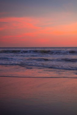 Kumsalda pembe gün batımı. Arka plan için deniz manzarası. Renkli gökyüzü. Güzel su yansıması. Ufuk çizgisinde güneş ışığı. Doğa ve çevre kavramı. Uzayı kopyala Endonezya, Bali 'de Günbatımı.
