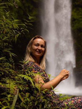 Genç beyaz kadın tropikal ormanda şelale manzarasının tadını çıkarıyor. Kadın portresi. Suyun enerjisi. Seyahat yaşam tarzı. Nung Nung Şelalesi, Bali, Endonezya
